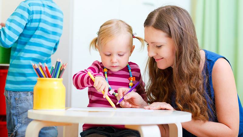 En pedagog och flicka ritar tillsammans.