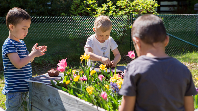 Barn leker vid blomlådor.