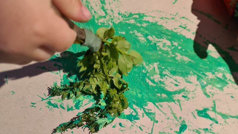 Målar grön färg med blåbärsris som pensel